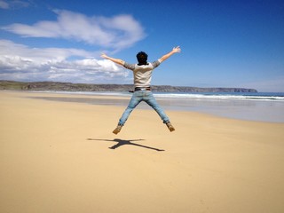Young man form behind jumping in an empty beach