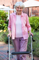 Elderly lady using a walker in the garden.