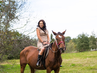 Fototapeta premium Elegant attractive woman riding a horse meadow