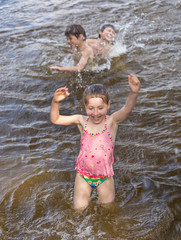 Fototapeta premium Little girl and her brothers are playing in a lake