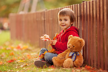 Adorable little boy with teddy bear in the park