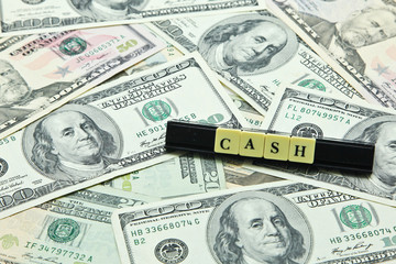 Word cash on pile of US dollar banknotes
