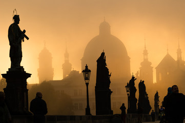 Silhouette of statue and tourists on Charles bridge during sunri