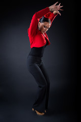 Young flamenco dancer in beautiful dress on black background.