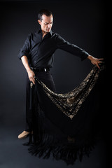 Young flamenco dancer in beautiful dress on black background.
