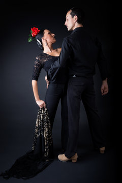 Young flamenco dancers in beautiful dress on black background.