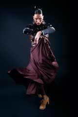Young flamenco dancer in beautiful dress on black background.