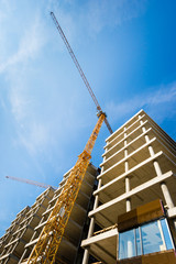 Construction site with building with yellow crane and blue sky