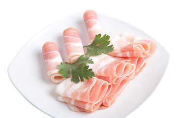 Bacon slices with parsley on a plate isolated on white backgroun
