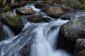 Fototapeta na wymiar Mountain stream cascading by rocks