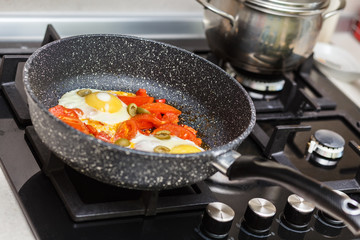 Frying pan with eggs and tomatoes