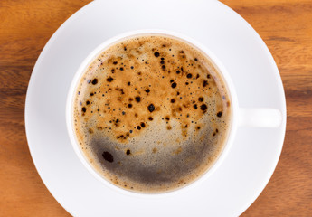 Top view of a cup of black coffee on wooden