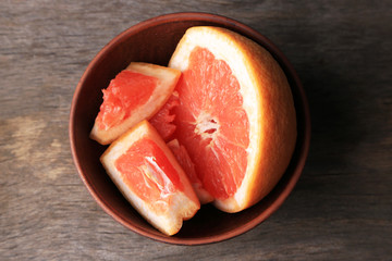 Ripe chopped grapefruit  in bowl, on wooden background