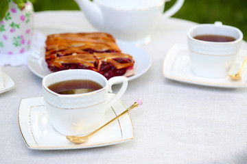Teacups and tasty pie on table, close-up, in garden