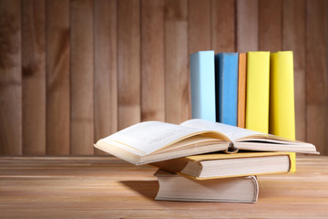Books on wooden table on wooden wall background