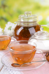 Teapot and cups of tea on table on bright background