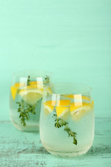 Tasty cool beverage with lemon and thyme, on wooden background