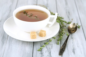 Cup of tasty herbal tea with thyme on wooden table