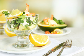 Tasty salads with shrimps and avocado in glass bowl and