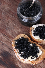 Slices of bread with butter and black caviar and glass jar of