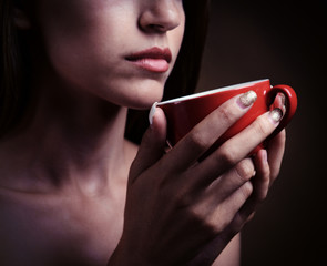Obraz premium Beautiful young girl with cup of coffee on brown background