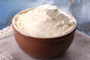 Fresh homemade butter in bowl, on color wooden background