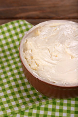 Fresh homemade butter in bowl, on wooden background