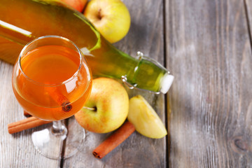 Apple cider in wine glass and bottle, with cinnamon sticks and