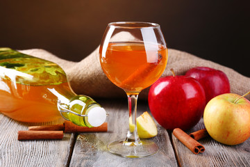 Apple cider in wine glass and bottle, with cinnamon sticks and