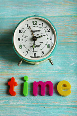 Time word formed with colorful letters on wooden background
