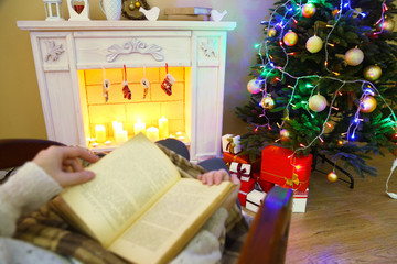Woman holding book in front of fireplace