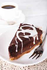 Piece of chocolate cake on plate and cup of tea on table