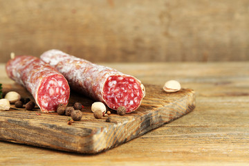 Italian salami on wooden cutting board, on wooden background