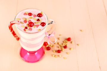 Cranberry milk dessert in glass, on color wooden background