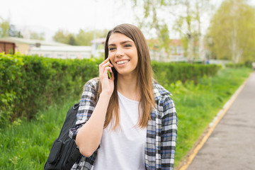 Young student girl talking on the phone outdoors. No retouch.