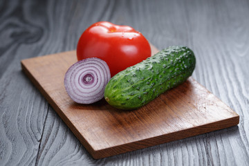 tomato, cucumber and onion on black wood table