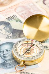 Compass on asian banknote concept financial direction