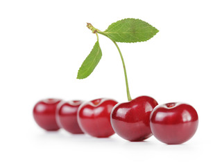ripe cherries in a row one with stem and leaf