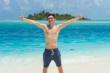 Happy man giving thumbs up sign at beach