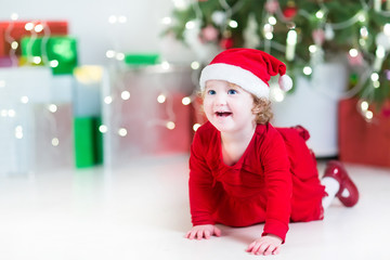 Laughing happy baby girl in santa hat between Christmas lights