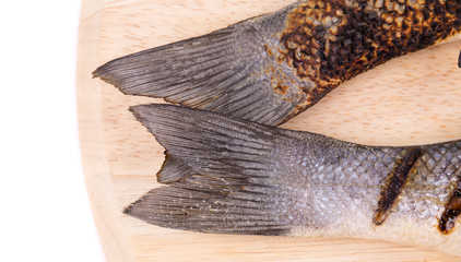 Two grilled seabass tails on platter.