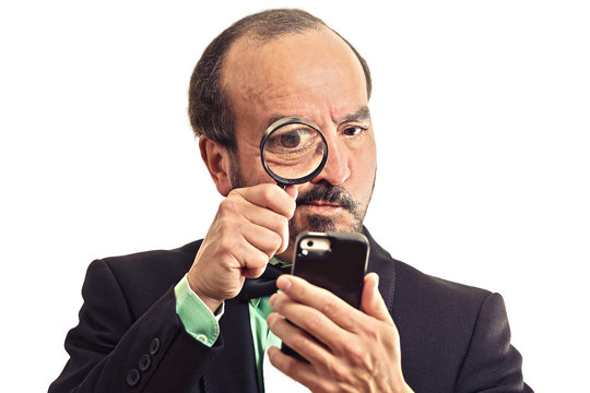 man looking through magnifying glass on smartphone
