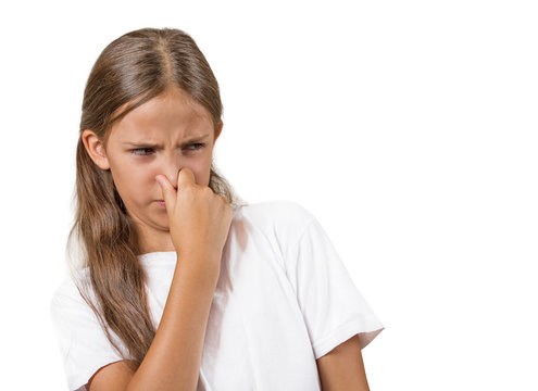 girl with disgust on face pinches nose on white background 
