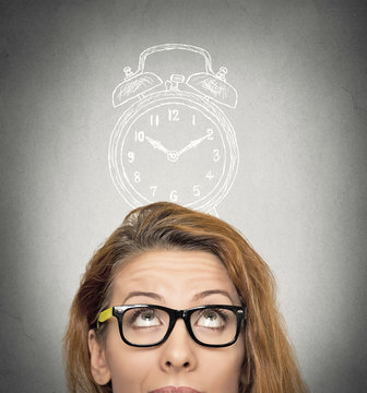 business woman with alarm clock above her head looking up