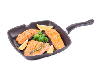 Fried salmon in pan with herbs.