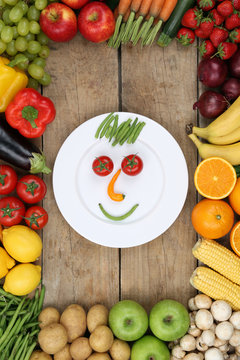 Gesicht aus Gemüse und Früchte auf Teller mit Tomaten und Äpf