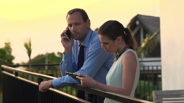 Business couple talking on cellphone and using tablet computer o