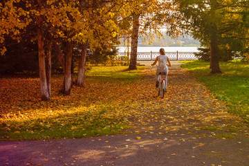A girl rides a bicycle in the autumn park.
