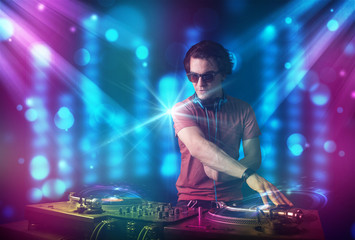 Fototapeta na wymiar Dj mixing music in a club with blue and purple lights