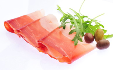 Sliced prosciutto with rosemary and olives on white background